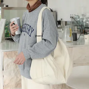 Bolso hobo grande de lona crema de estilo japonés llevado por una modelo en un café