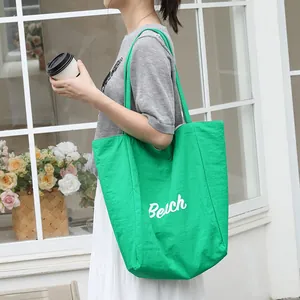 Elegante bolso tote de nailon verde con estampado 'Beach' en un entorno de estilo de vida