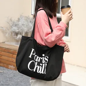 Vista detallada del bolso de lona negra con estampado Paris Chill y atuendo informal