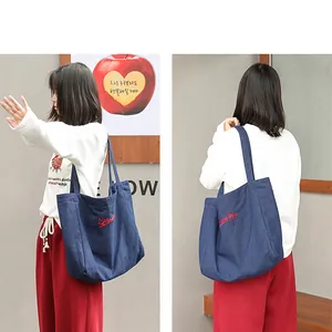 Vistas detalladas de un bolso tote de lona denim azul oscuro con bordado rojo.