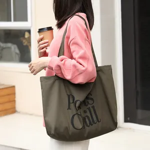 Bolso de lona verde oliva informal con estampado gráfico Paws Chill sostenido por mujer.