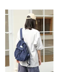 Mochila informal de lona azul marino con cordón mostrada en una modelo femenina.