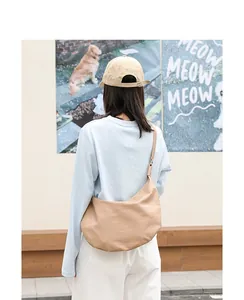 Modelo con un bolso bandolera de piel sintética suave de color beige, vista trasera