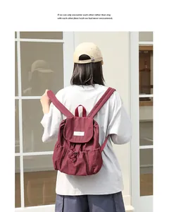 Vista posterior de una mujer con una elegante mochila de lona granate con cordón ajustable