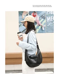 Detalle de bolso de media luna en piel sintética suave negra estilo japonés.