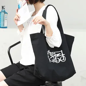Elegante bolso de lona negra con estampado gráfico, llevado por una modelo