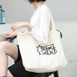 Bolso tote de lona blanca con diseño abstracto negro llevado por modelo en entorno casual