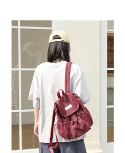 Vista posterior detallada de una mujer con una mochila informal de lona granate con cordón.