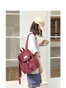 Modelo asiática con una elegante mochila de lona granate con cierre de cordón.