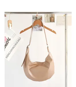 Elegante bolso hobo beige de cuero PU suave colgado de una percha de madera natural