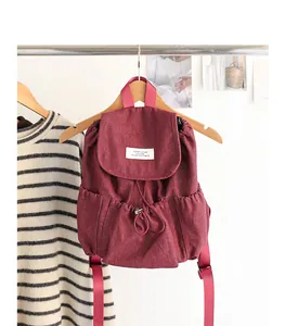 Mochila vintage de mezclilla granate con cordón colgada en una percha de madera