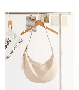 Bolso de hombro hobo minimalista de cuero PU suave crema colgado de un perchero de madera.