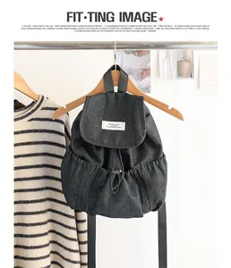Vista detallada de una mochila denim gris oscuro con cordón y etiqueta blanca en la solapa.