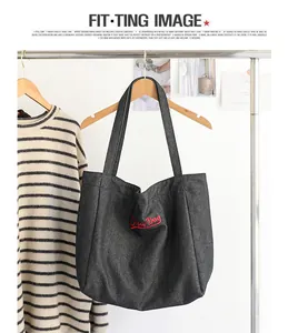 Detalle del bolso tote de mezclilla retro con bordado rojo Super Dog colgado en percha