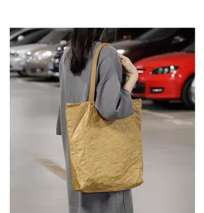 Casual DuPont paper shoulder bag with wrinkled texture worn by model in parking lot