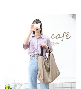 Modella asiatica con borsa a tracolla in nylon kaki di grande capacità in un caffè
