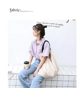 Grande borsa tote minimalista in tela beige mostrata in uno scatto lifestyle con modella