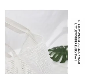Primer plano de la tela de malla blanca y el asa de lona de un bolso playero elegante.