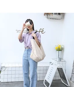 Modella asiatica con una borsa tote beige grande e minimalista in un ambiente café