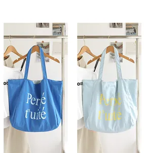 Close-up of casual nylon tote bag with Perpétuité letter print and stripe lining detail