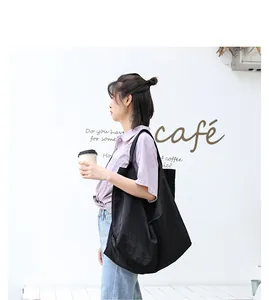 Grande borsa tote nera mostrata in un ambiente café con modella asiatica