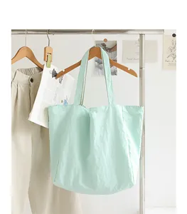 Large mint green nylon tote bag hanging on a stylish minimalist white clothing rack