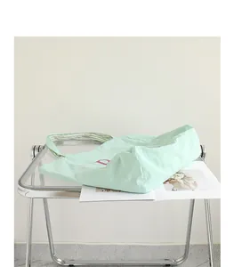 Casual light green nylon tote bag with pink letter print on a modern clear table