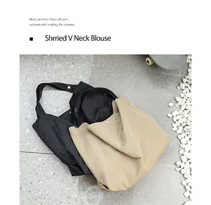 Dettaglio di due borse tote minimaliste in nylon nero e kaki su pavimento in pietra