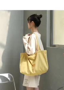 Large yellow canvas tote bag in minimalist Mori style carried by a model.