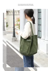 Vista detallada de un bolso shopper de pana verde con bordado usado en una calle de ciudad