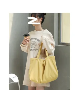 Detailed view of a minimalist yellow canvas tote bag being carried by a model in a casual setting