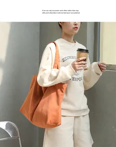 Model showcasing a large orange canvas tote bag in a minimalist lifestyle setting