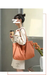 Minimalist large orange canvas tote bag carried by a model in a lifestyle setting
