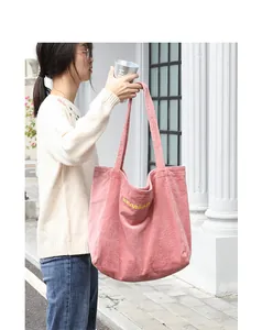 Foto lifestyle de un bolso shopper de pana rosa con bordado de letras amarillas