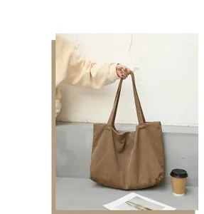Detailed shot of a brown canvas tote bag held by hand in a minimalist setting