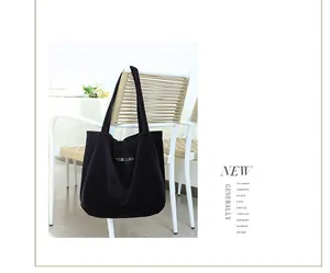Bolso de pana negro con bordado de letras colgado en una silla blanca moderna.