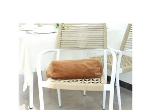 Vista detallada de un elegante bolso de pana marrón descansando en una silla tejida blanca