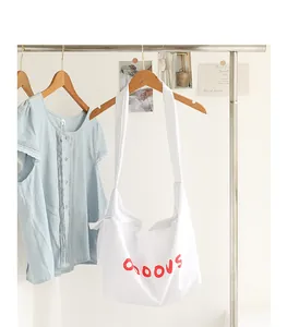 Detailed shot of white nylon crossbody bag with red letter print and knot strap
