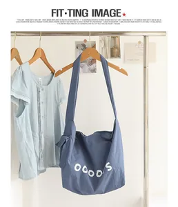 Minimalist blue nylon crossbody bag featuring a knotted strap and white letter print