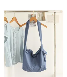 Detailed shot of a blue nylon messenger bag with knot hanging on a garment rack