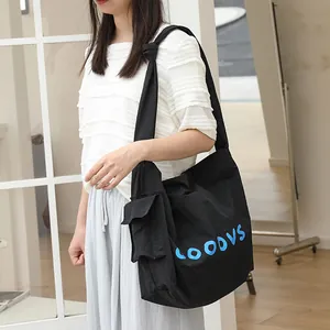 Casual Japanese style black nylon crossbody bag with blue lettering and unique knot shoulder strap