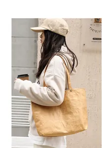Model carrying a wrinkled DuPont paper tote bag in a casual outdoor street setting