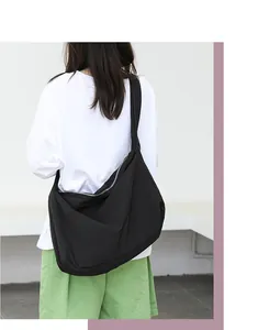 Rear view of a minimalist black nylon crossbody bag worn over a white t-shirt