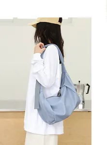 Vista lateral de un bolso hobo minimalista de cuero PU azul claro plisado con modelo.