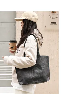 Close-up of black Tyvek tote bag with vintage wrinkled texture carried by model