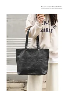 Detailed view of a black crinkled DuPont paper tote bag held by a model.