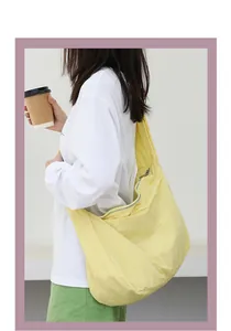 Detail shot of a yellow nylon shoulder bag worn by a model in a casual lifestyle setting.