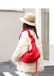Close-up view of a vibrant red corduroy shoulder bag with ruffled strap and drawstring