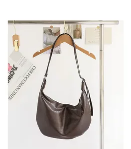 Elegante bolso hobo minimalista de cuero PU suave marrón oscuro colgado de una percha