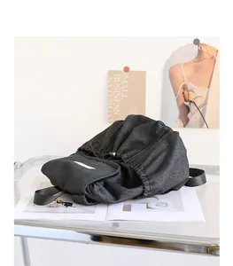 Vista detallada de una mochila de lona negra plisada sobre una mesa de vidrio moderna